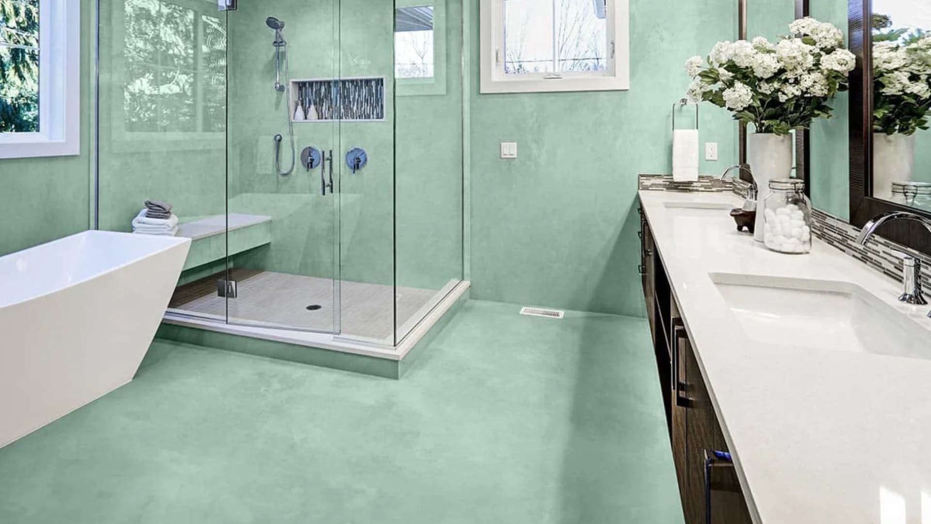 Green microcement bathroom with walk-in shower and white vanity in Saudi Arabia